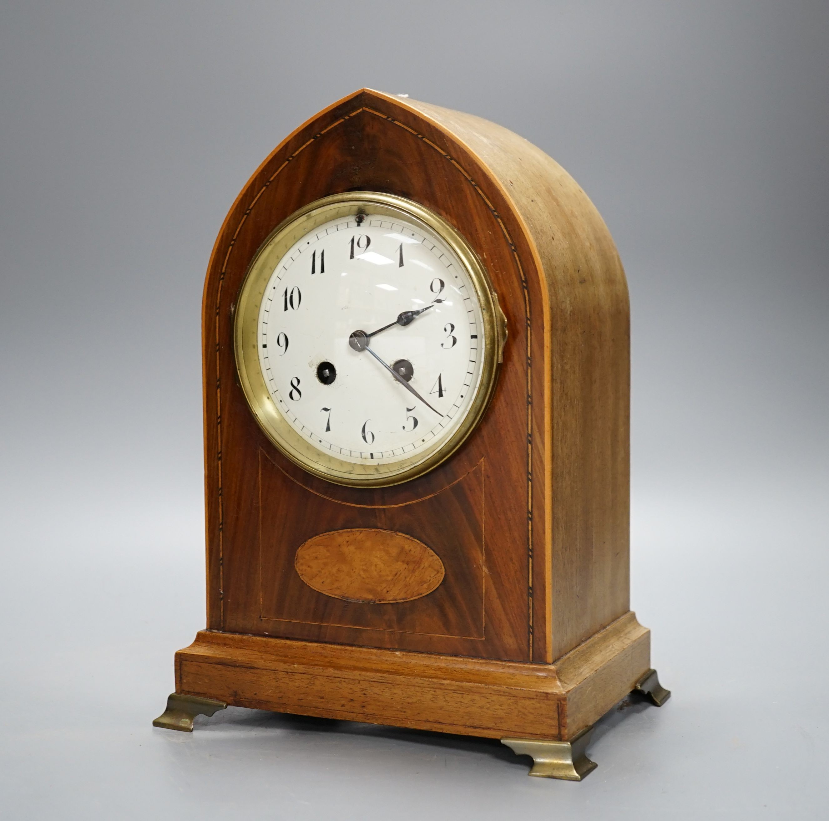 An Edwardian mahogany mantel clock, lancet top case, with white enamelled dial. Key and pendulum. 29cm